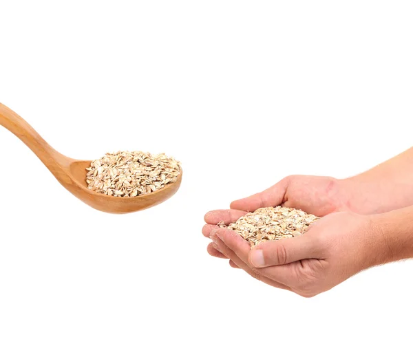 Oatmeal flakes into wooden spoon and hand. — Stock Photo, Image