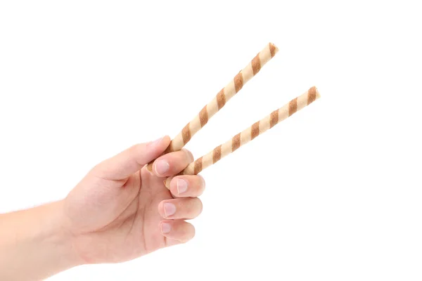 Hand holds striped chocolate wafer rolls. — Stock Photo, Image