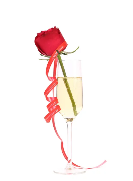 Rose in glass of champagne and streamer. — Stock Photo, Image