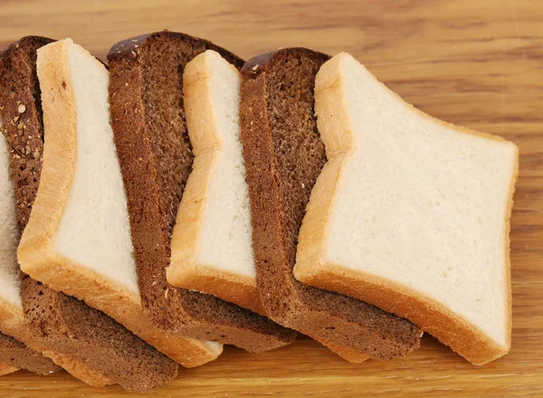 Biały i brązowy bochenek chleba na drewnianym stole. — Zdjęcie stockowe