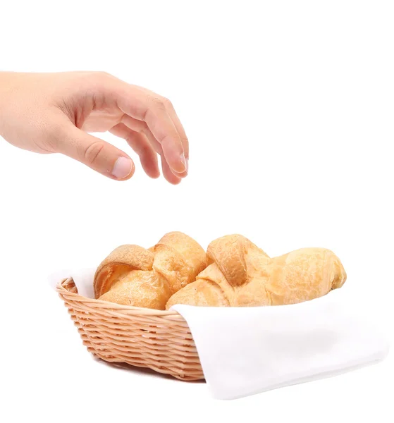 Hand reaches for the croissants in a basket. — Stock Photo, Image