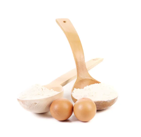 Wooden spoons with flour and two eggs. — Stock Photo, Image