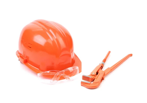 Red safety helmet and adjustable pipe wrench. — Stock Photo, Image