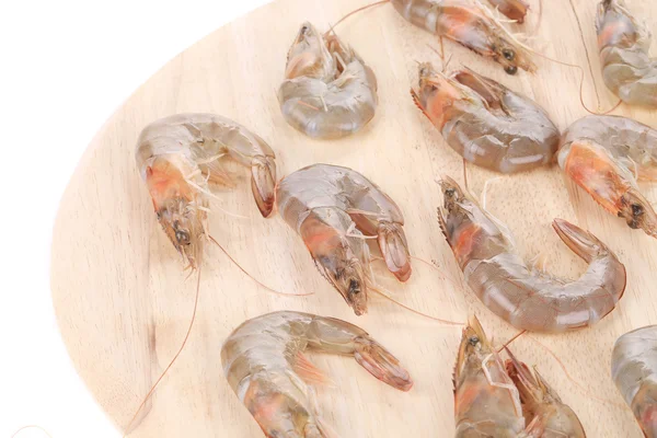 Raw shrimps on wooden round board. — Stock Photo, Image