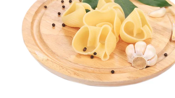 Italiaanse pasta schelpen op een houten bord. — Stockfoto