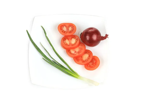 Vårlök och skivad tomat på plattan. — Stockfoto