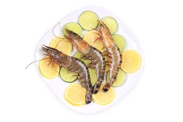 Raw shrimps on plate with lemon and lime. — Stock Photo, Image