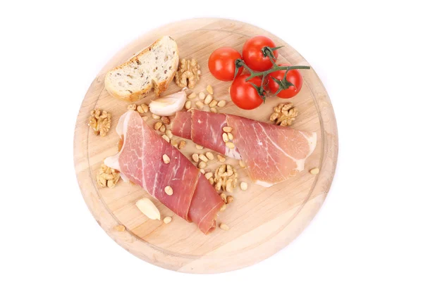 Prosciutto with tomatoes on wooden platter. — Stock Photo, Image