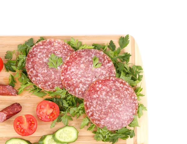 Sausage salami and vegetables on wooden platter. — Stock Photo, Image