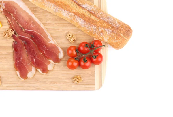 Prosciutto com tomates em travessa de madeira . — Fotografia de Stock