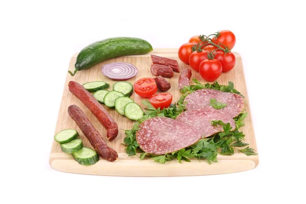 Колбасные салями и овощи на деревянном блюде . — стоковое фото