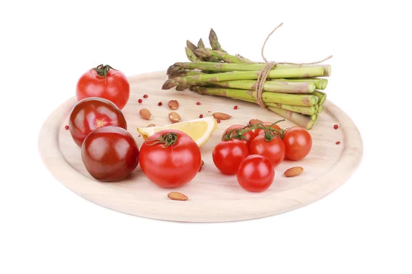 Espárragos y tomates sobre tabla de madera . — Foto de Stock