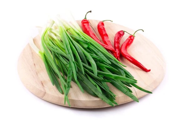 Red peppers and scallions on the wooden board. — Stock Photo, Image