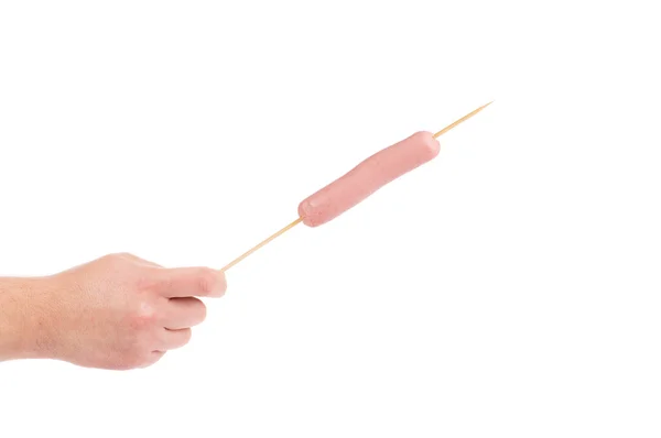 Hand holds sausage on stick — Stock Photo, Image