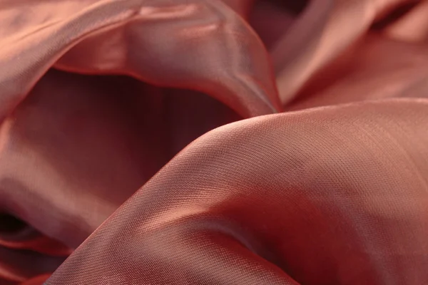 Kumaşın dokusu yakından kahverengidir. Dalgalı kumaştan yapılmış güzel soyut arkaplan.