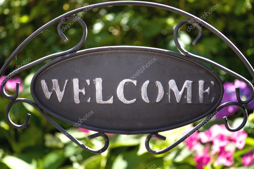 Iron welcome sign in the garden with hydrangea on the background
