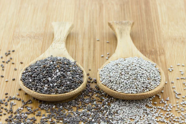 Black and white chia seeds on wooden spoon — Stock Photo, Image