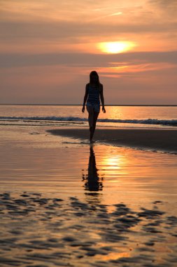 gün batımında denizde yürüyen kız