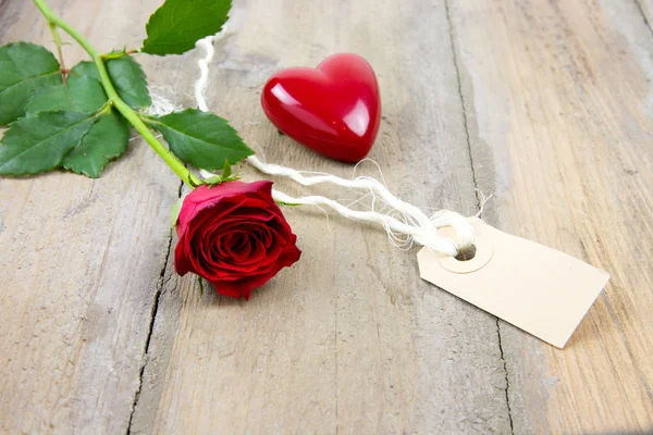 Red rose, label tag and plastic heart — Stock Photo, Image