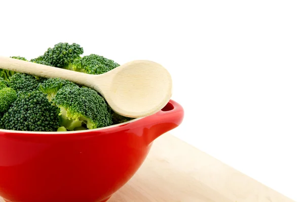 Red bowl with broccoli and wooden spoon on it — Stock Photo, Image