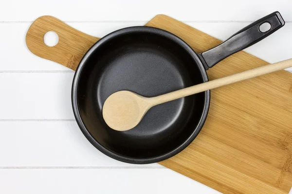 Tabla de cortar con sartén y cuchara de madera —  Fotos de Stock