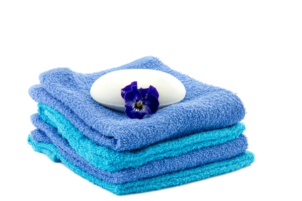Bar of soap on piled towels and pansy flower — Stock Photo, Image