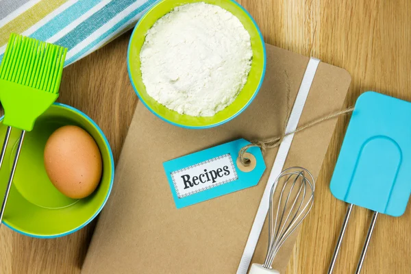 Ovo, farinha e utensílios de cozinha no livro de receitas — Fotografia de Stock