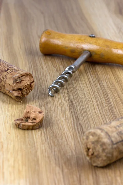 Corkscrew met kurken op houten oppervlak — Stockfoto