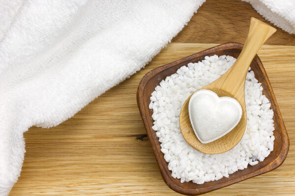 Wooden spoon in bowl filled with bath salt and towel