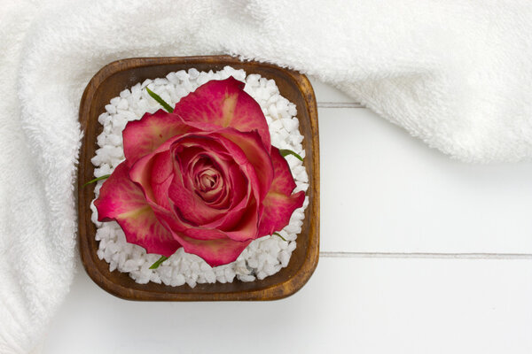 White towel and wooden bowl filled with bath salt