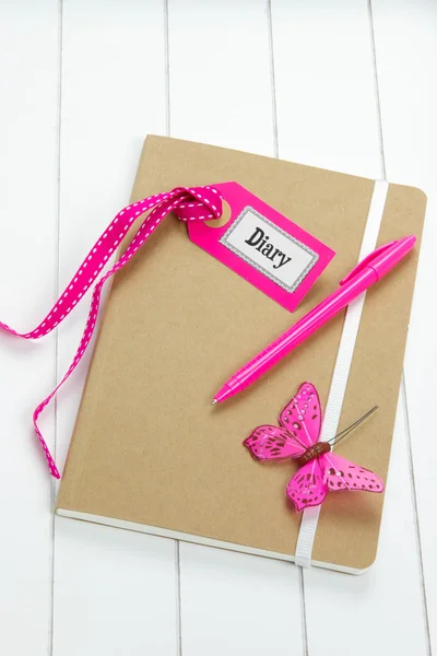 Deník s růžovým zdobením na dřevěné desce — Stock fotografie