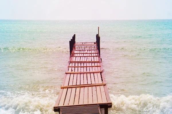 Old wooden bridge in the sea in a retro style — Stock Photo, Image