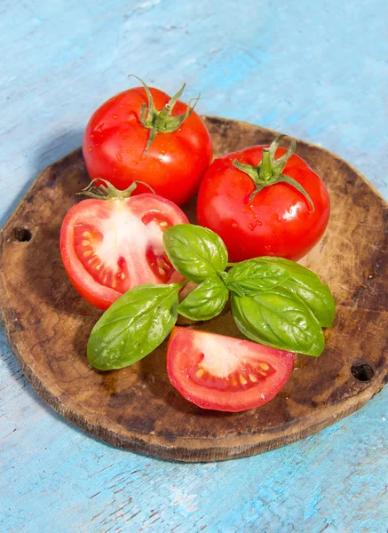 Tomate avec feuille de basilic sur un fond bleu pâle en bois — Photo
