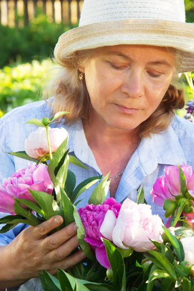 Женщина в саду заботится о пионах — стоковое фото