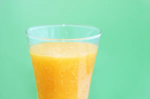 Повна склянка апельсинового соку на зеленому фоні — стокове фото