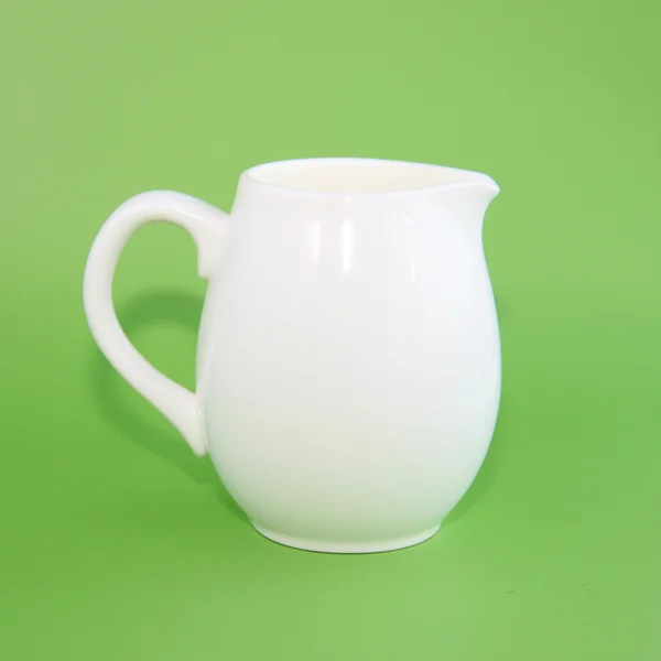 Керамика для молока на зеленом фоне — стоковое фото