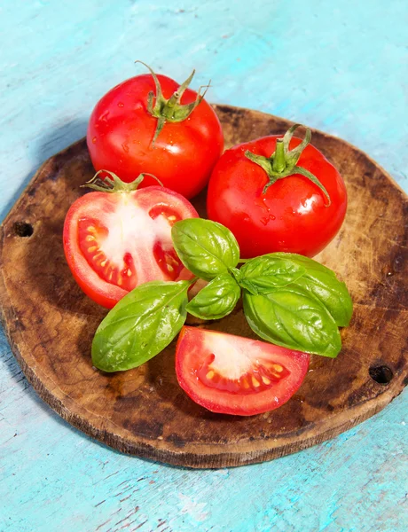 Tomate avec feuille de basilic sur un fond bleu pâle en bois — Photo