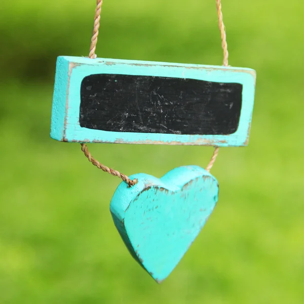 Hjärtat tecken hängande på en bakgrund av grönt gräs. kort skärpedjup — Stockfoto