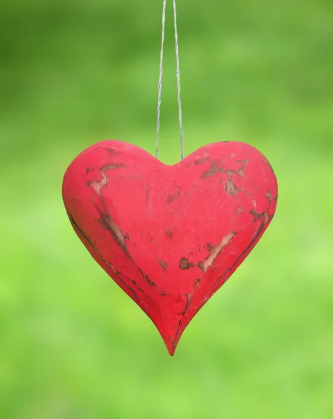 Vintage red heart hanging on a background of green grass — Stock Photo, Image