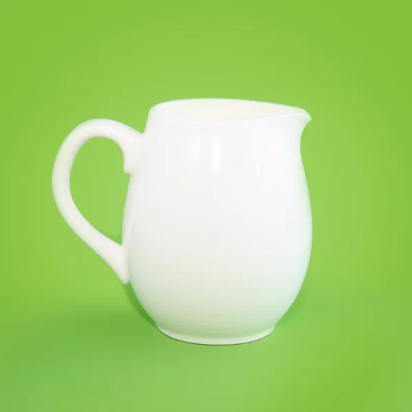 Bílý malý džbán na zeleném pozadí — Stock fotografie