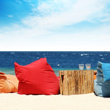 Soft chairs on the beach overlooking the ocean clipart