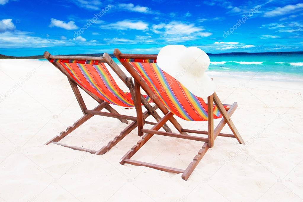 Two wooden sun loungers on white sand