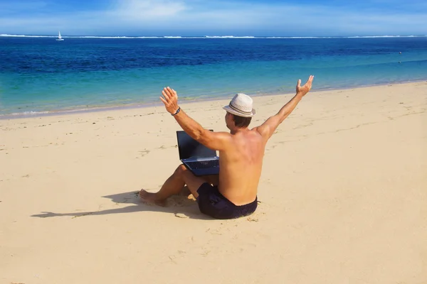 Homme travaillant avec un ordinateur portable sur la plage — Photo