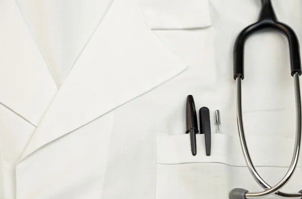 Лікар скраби зі стетоскопом, термометром і ручками в кишені — стокове фото