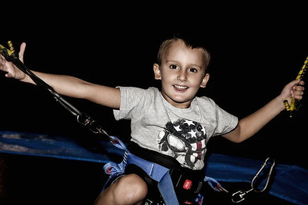 Kind spelen met bungee koorden in de nacht — Stockfoto