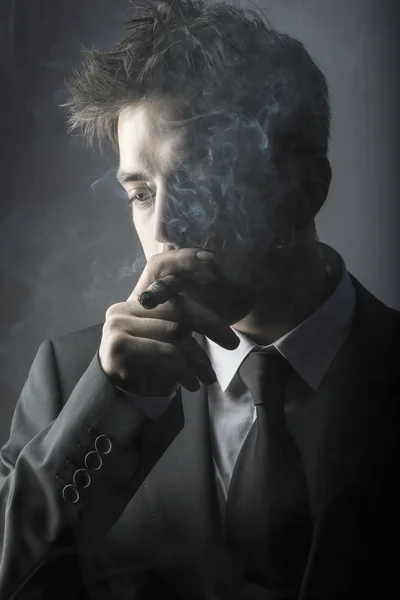 Joven hombre elegante fumando un cigarro —  Fotos de Stock