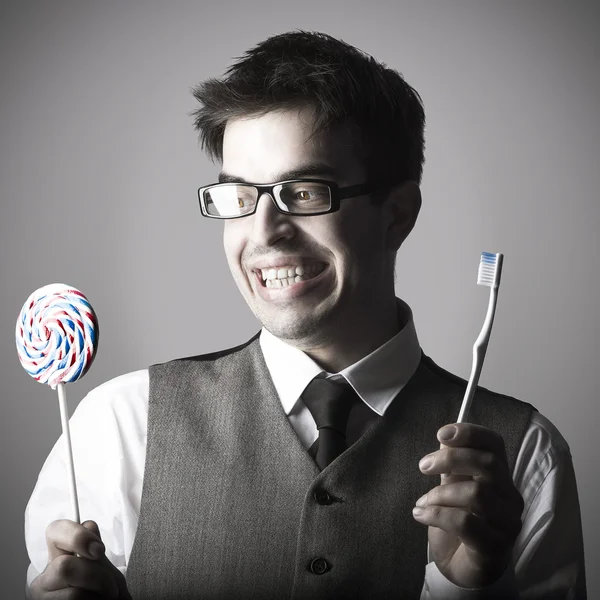 Gelukkig slimme jonge man met lolly en tandenborstel — Stockfoto