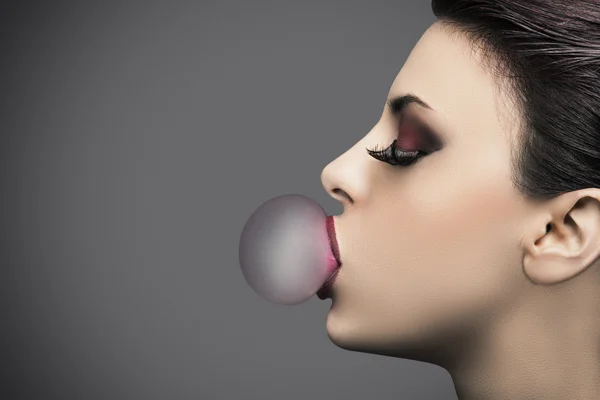 Belleza joven mujer hace un globo con una goma de mascar — Foto de Stock