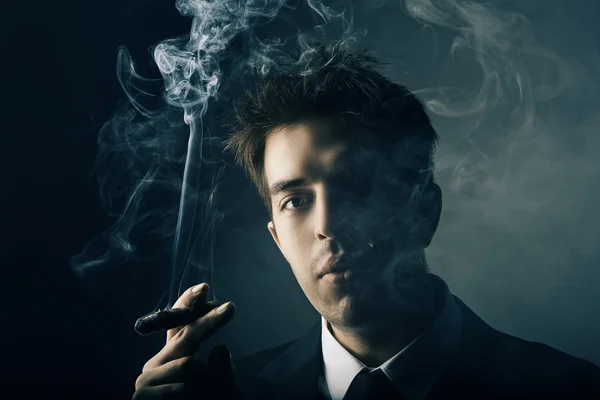 Молодой красивый стильный мужчина курит сигары — стоковое фото