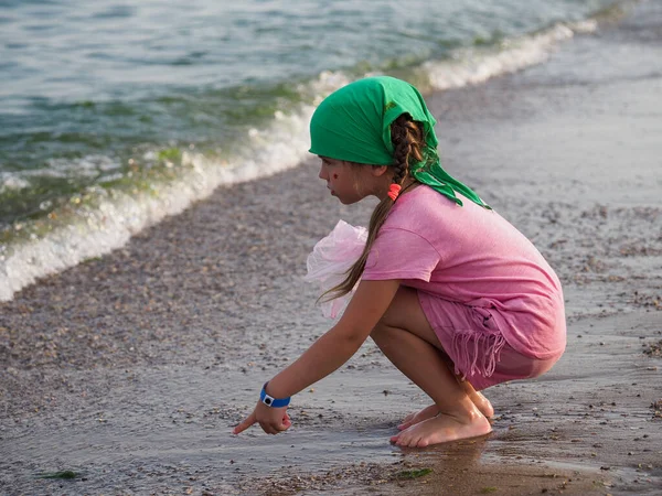 緑のバンダナのウクライナの女の子は砂浜で貝殻を収集します — ストック写真